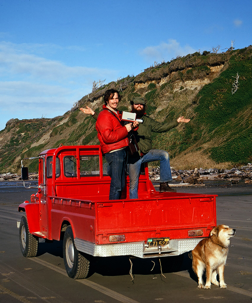 Photo of Bill Bradley and a friend in a red Toyota truck on Whiskey Run Beach, with Bill's dog Brutus sitting next to the truck.